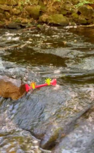 A handmade dam in a stream keeping a toy boat from going downstream
