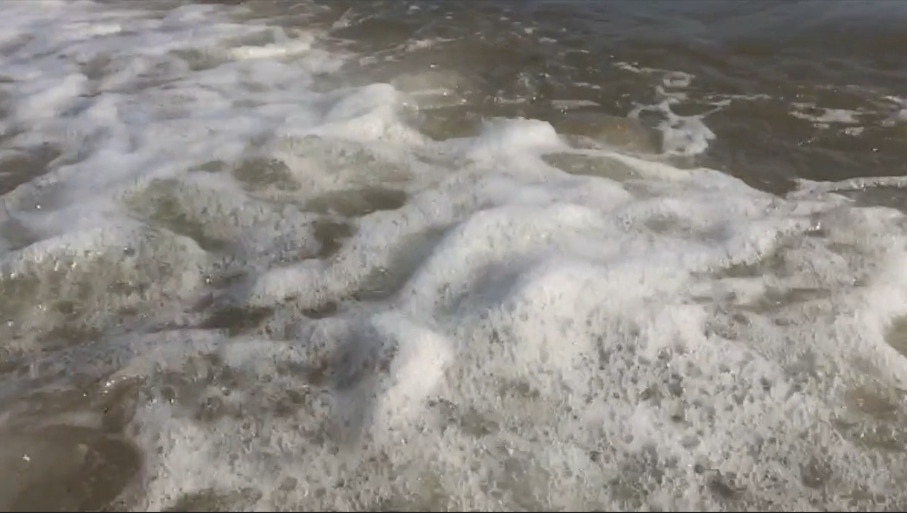 Water receding on the beach with foam